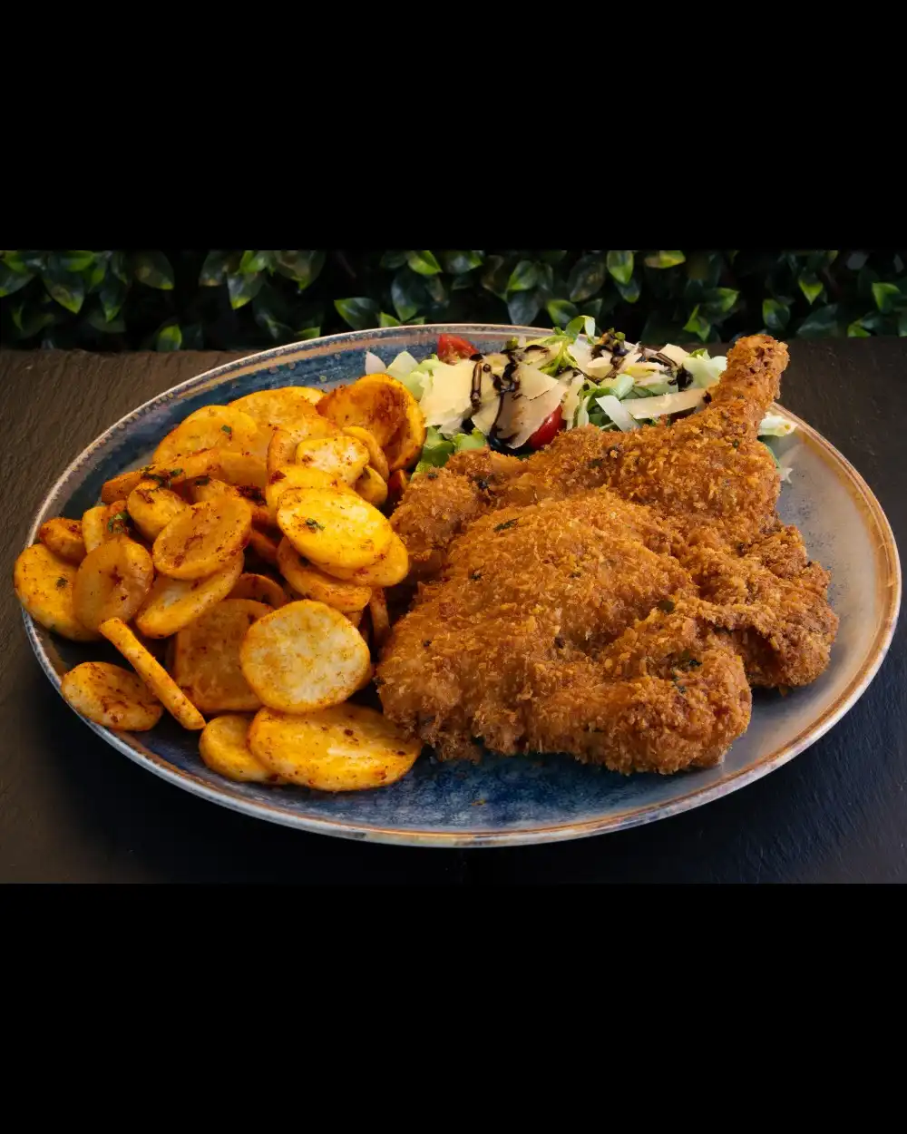 Tomahawk de Porc în Crustă de Parmezan — Platouri Principale — Tony's Eat & Drink — Ingrediente: cotlet de porc cu os, crustă de panko și parme…